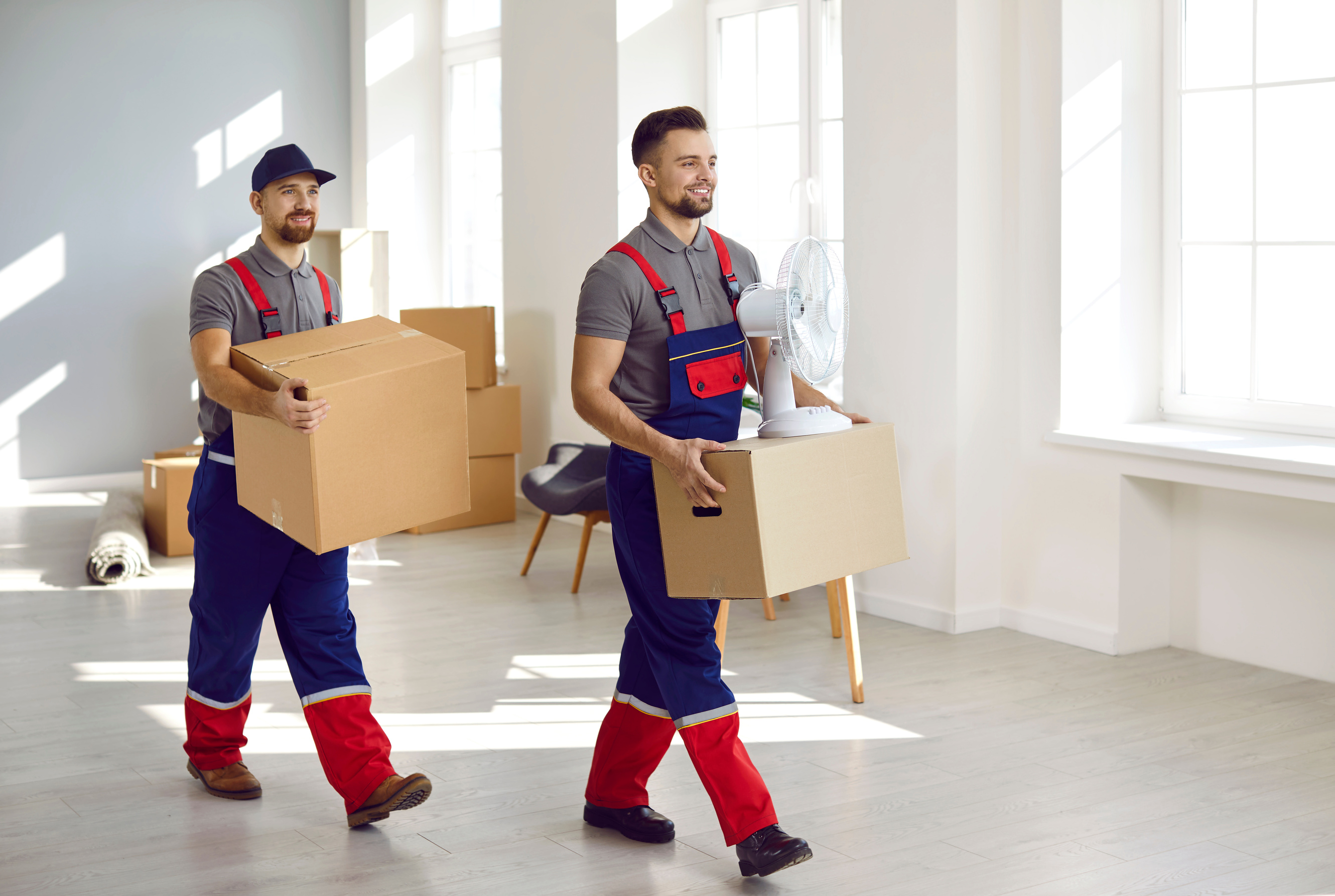 Young Workers from Moving Company and Delivery Service Removing Boxes from Apartment